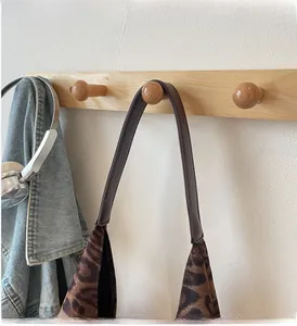 Dettaglio della borsa leopardata appesa a un gancio con comodi manici marroni