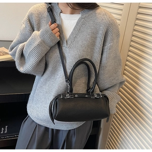 Detailed view of black cylinder bag with white stitching and silver hardware on a model
