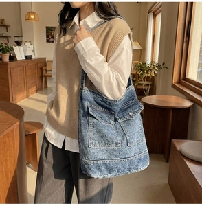 Close-up of blue denim tote bag with dual front pockets and metal buckle details