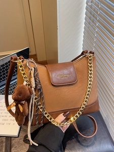 Quilted caramel patchwork shoulder bag with gold chain and bag charm in office setting