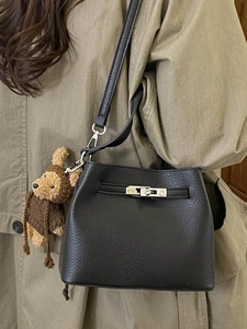 Black pebble leather bucket bag with silver lock and teddy bear charm on model
