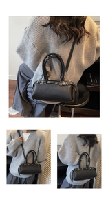 Detail of black lychee grain leather Boston bag with buckle accents and adjustable strap