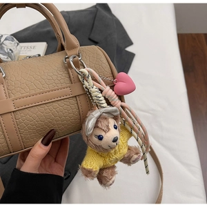 Detail of cute plush bear charm with yellow sweater on brown lychee leather handbag