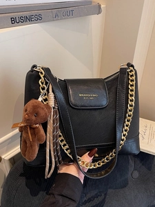 Elegant black quilted leather shoulder bag with gold chain and brown plush bear charm