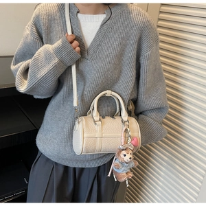 Chic beige boston bag with lychee grain texture and cute plush charm on a model
