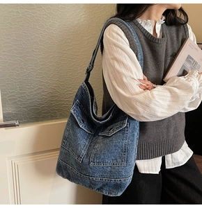 Detail of vintage blue denim tote bag featuring dual front pockets and adjustable strap
