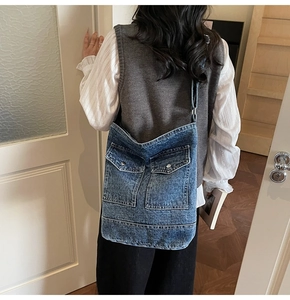 Detail of blue denim crossbody tote bag featuring utility pockets and adjustable strap