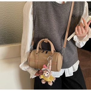 Close-up of khaki Boston bag with lychee texture and cute bear plush charm accessory