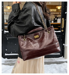 Quilted tote bag in burgundy crinkled leather with gold chain strap in snow cafe setting