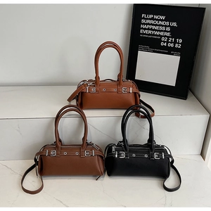 Close-up of three textured leather Boston bags in black, caramel, and tan with silver buckles