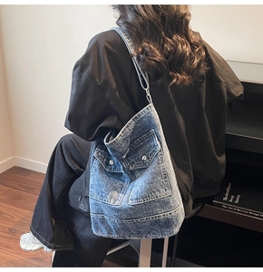Detail of washed blue denim tote bag with cargo pockets and silver hardware finish