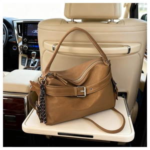 Detailed close-up of brown vintage leather tote bag with star charm in car interior