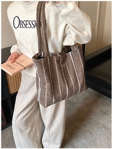 Brown vertical striped tote bag with silver bow detail worn by model in autumn style