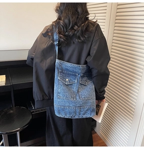 Rear view of a model wearing a large blue denim tote bag with dual front pockets