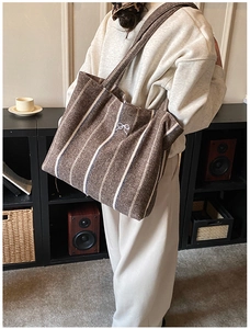 Detailed texture of brown vertical striped cotton tote bag with white bow accent
