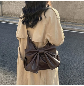 Back view of a large brown leather tote bag with a retro oversized lace-trimmed bow detail