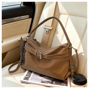 Detailed shot of brown oversized leather hobo bag with star charm on car seat