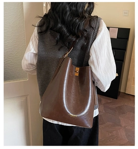 Dark brown retro bucket bag with polished leather and metal turn-lock on model
