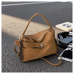 Close-up of tan leather tote bag with star charm and striped scarf on urban pavement