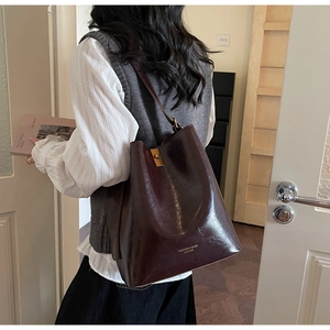Detail view of large dark brown bucket bag in glossy oil wax leather with gold lock