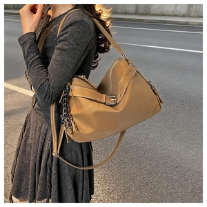 Detail of large brown leather tote bag with stylish buckle and woven tassel accent