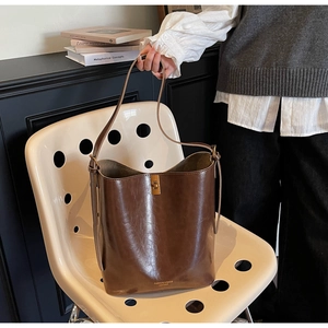 Macro shot of dark brown oil-wax leather bucket bag with gold metal twist lock detail