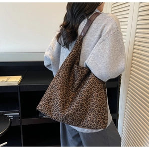 Detail of leopard print tote bag with wide brown leather strap and soft fabric texture