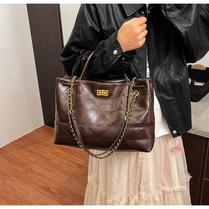 Detailed view of the dark brown quilted tote bag with golden lock and chain strap