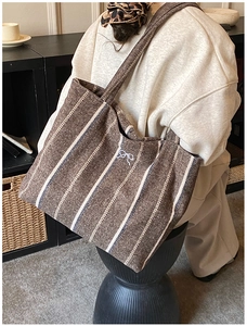 Close-up of a striped tote bag featuring fine herringbone texture and bow embroidery