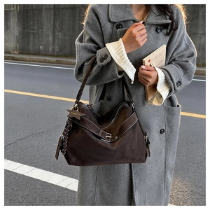 Close-up of vintage brown suede tote bag with decorative star pendant and strap detail