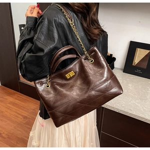 Close-up of vintage brown quilted tote bag with golden lock and chain strap