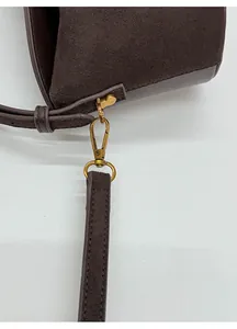 Détail macro d'un sac en daim marron avec crochet doré antique et coutures fines