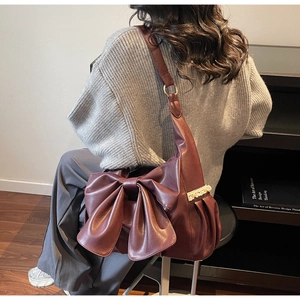 Detail of burgundy tote bag with large bow and lace trim worn by a model in casual style