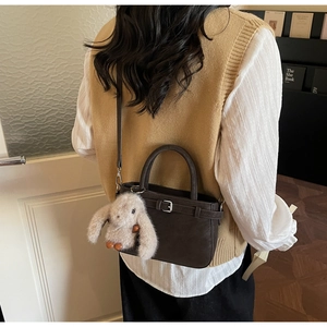 Detail of dark brown vintage bucket bag with rabbit charm and adjustable shoulder strap