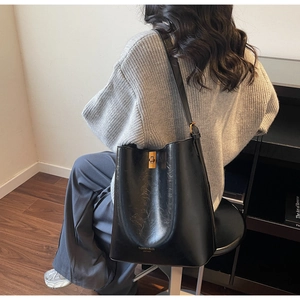Detail of black leather bucket bag with gold metal twist lock and fashion lettering
