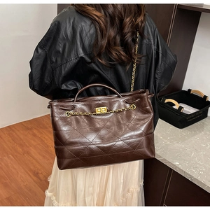Detail of dark brown quilted tote bag with golden twist lock and chain strap for women