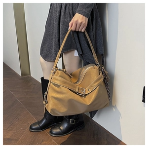 Detail of caramel faux leather tote bag showing buckle decor and textured surface