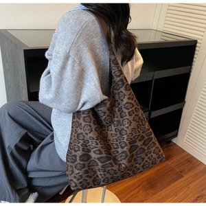 Détail d'un grand sac cabas à motif léopard porté à l'épaule par un mannequin en intérieur