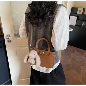 Sac seau en cuir marron avec charme de lapin en peluche porté par un mannequin