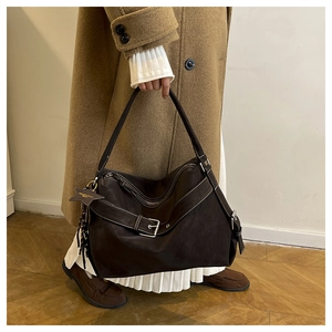 Detail of dark brown leather tote bag featuring contrast stitching and star charm pendant