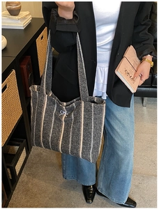 Detail of grey striped tweed tote bag featuring an elegant white bow accent on top