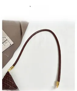 Close-up of deep brown woven leather bag featuring round shoulder straps and gold hardware