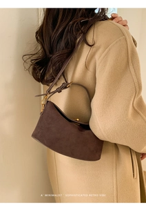 Sac bandoulière en daim marron foncé porté avec un manteau minimaliste au style rétro