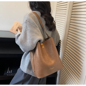 Detail of a brown vintage leather bucket bag with metal buckle and fashion logo lettering