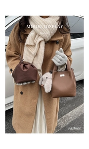 Detail view of lychee texture leather tote with drawstring pouch and plush bunny accessory