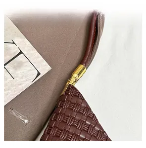 Detail of golden hardware and cross-woven texture on dark brown tote bag