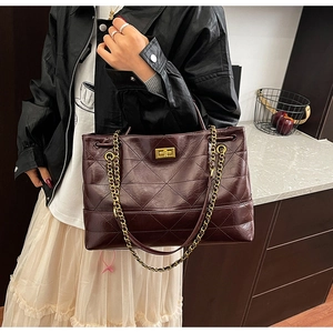 Detail of burgundy quilted leather tote bag with gold chain strap and turn-lock closure