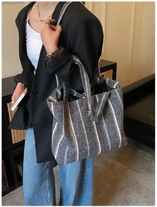 Detail of grey striped tote bag showing woven texture and spacious interior on a model