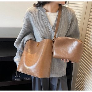 Close-up of brown leather bucket bag set with golden hardware lock and inner pouch