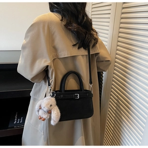 Black matte bucket bag with long-ear rabbit plush pendant shown on a model